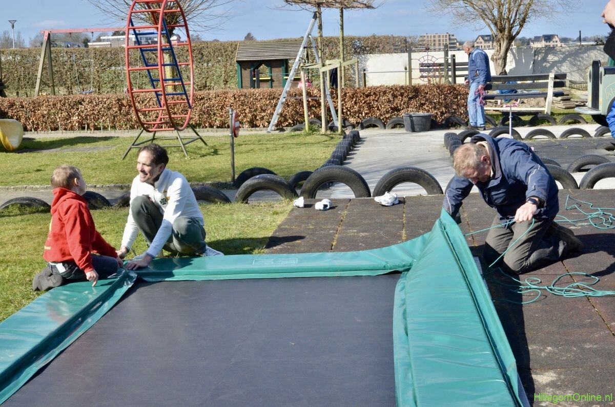 Vrijwilligers plaatsen samen met kinderen de nieuwe trampoline