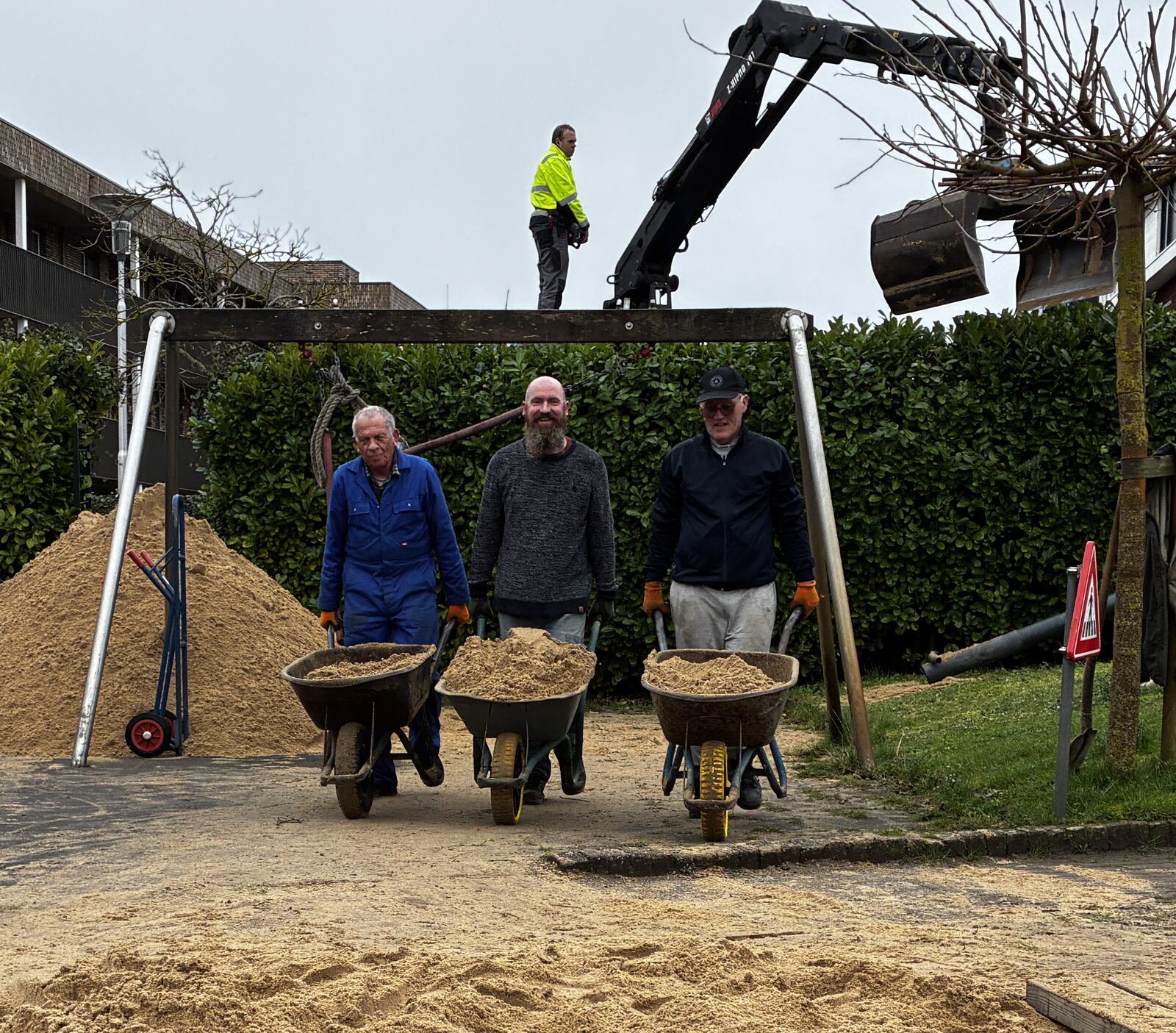 Vrijwilligers scheppen zand voor de speeltoestellen