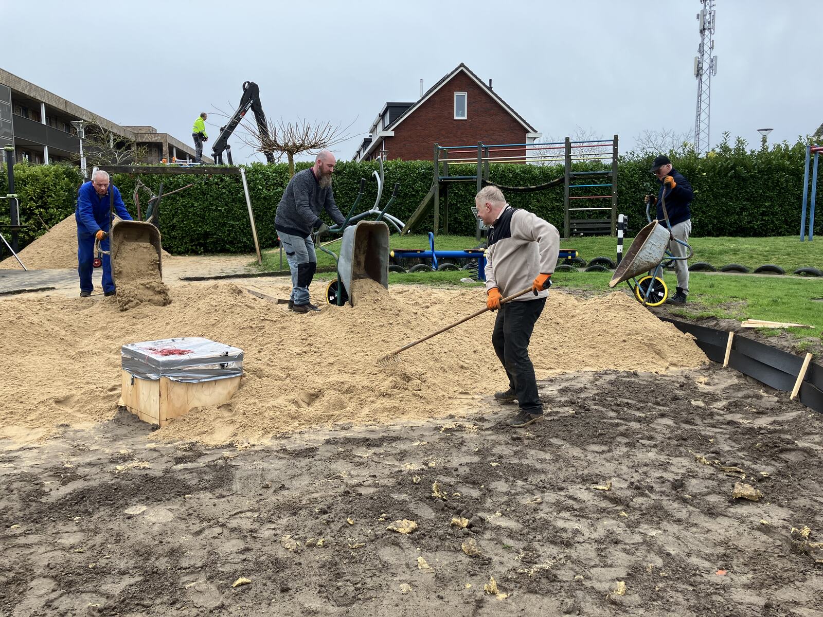 Vrijwilligers scheppen samen nieuw zand in de speeltuin