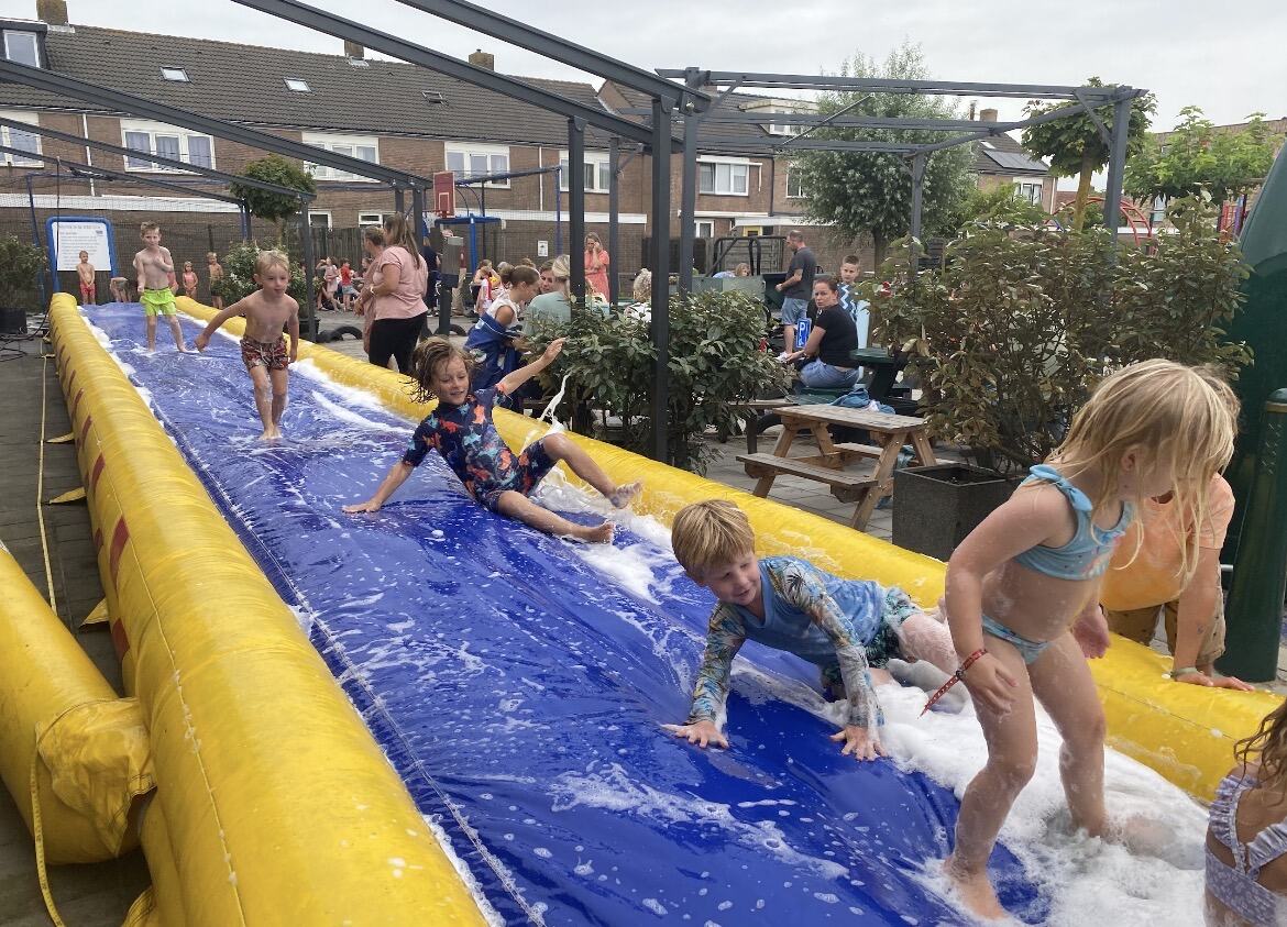 Kinderen glijden en spelen op de zeepglijbaan