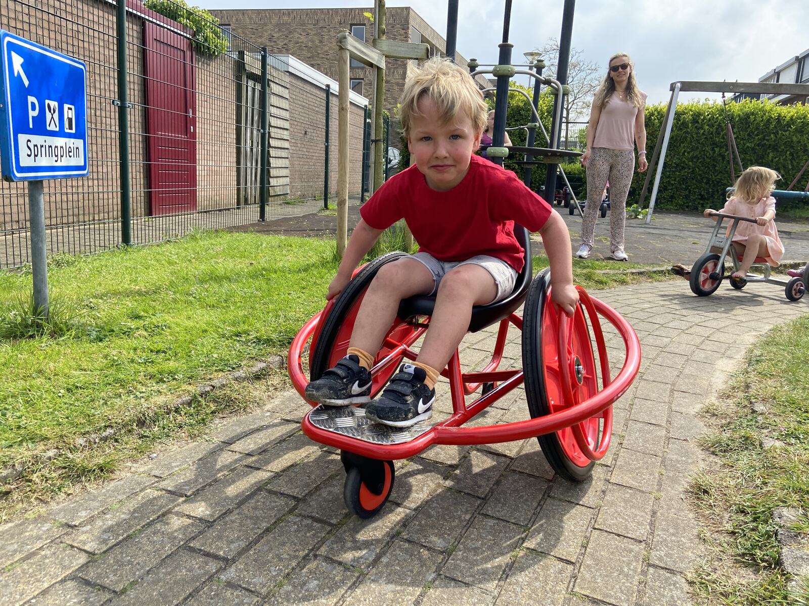 Kind rijdt op de rode wheely-car in de speeltuin
