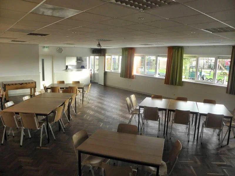 De grote zaal van Speeltuin Weerestein met tafels en stoelen